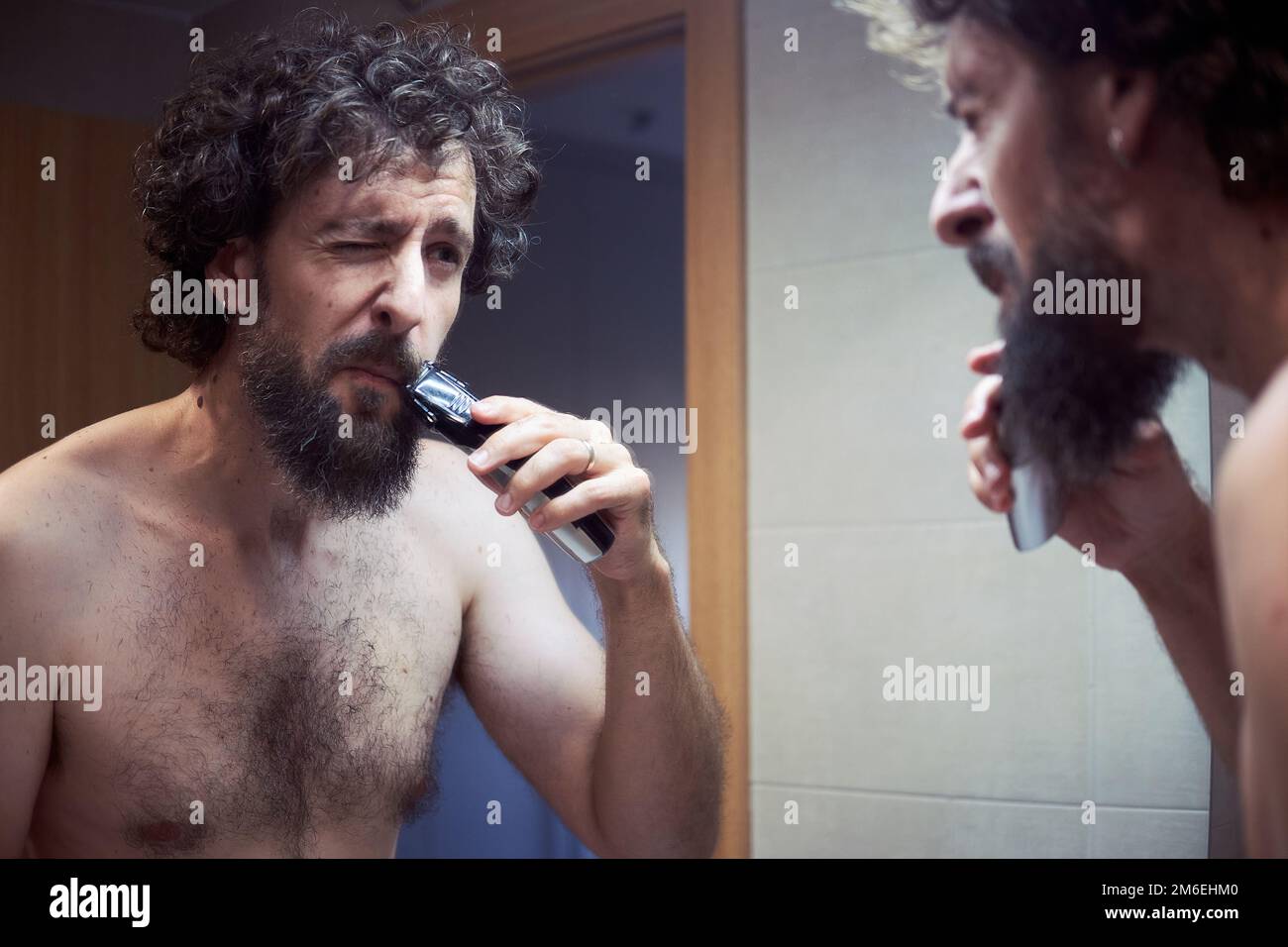 Homme hispanique d'âge moyen coupant sa barbe Banque D'Images