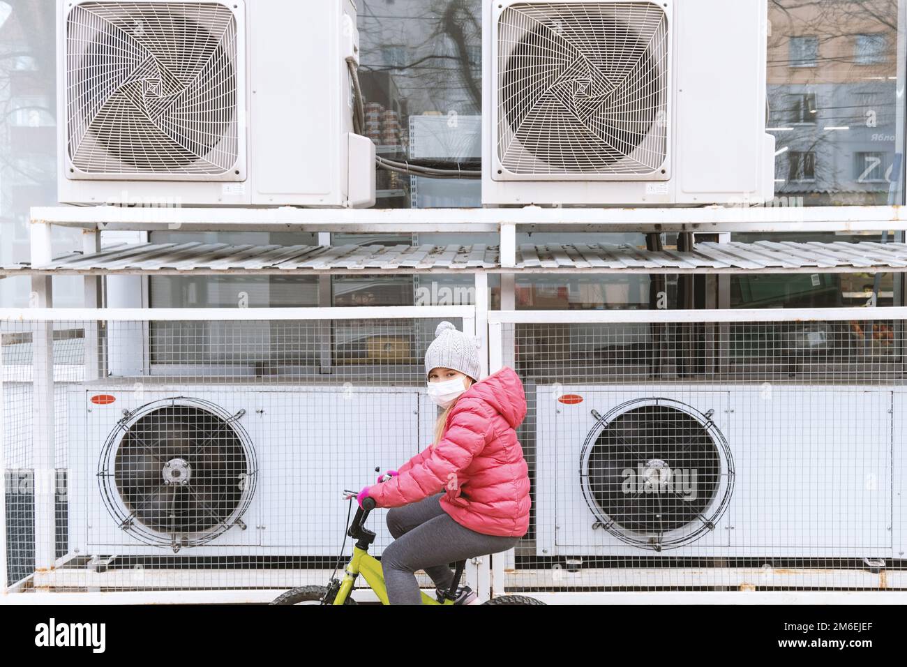 Jeune fille blonde en veste rose à vélo Banque D'Images