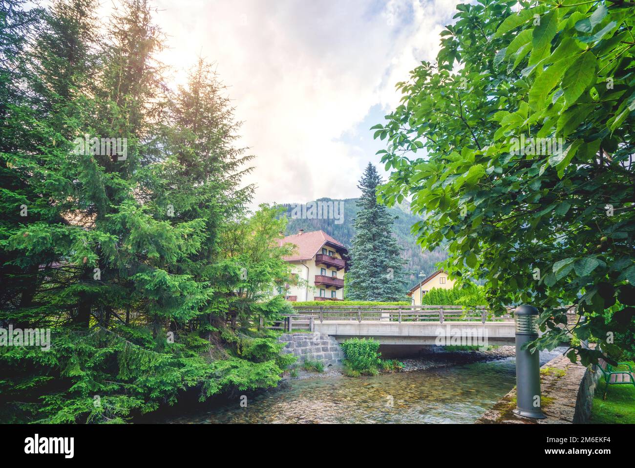 Petit pont au-dessus d'un ruisseau dans un petit village autrichien avec des montagnes en arrière-plan Banque D'Images