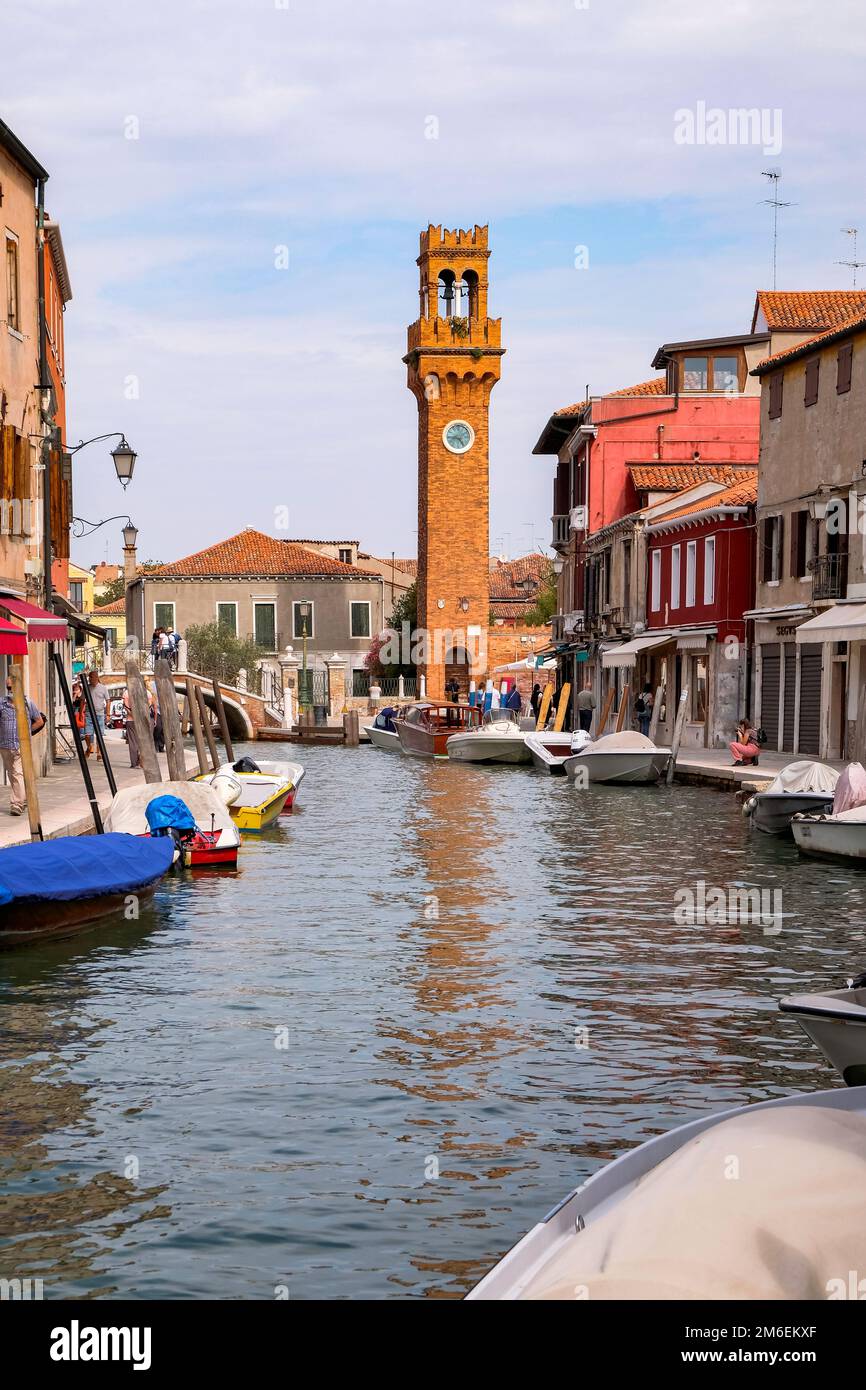 Bateaux de pêche et maisons vénitiennes colorées le long du canal aux îles de Murano, avec Torre dell'Orologio en arrière-plan Banque D'Images