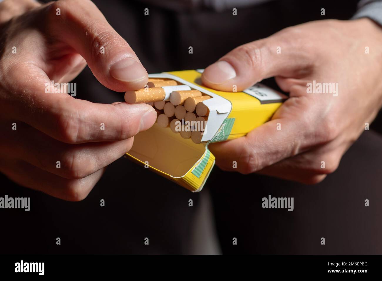 gros plan homme main tenant peler le paquet de cigarettes préparer fumer  une cigarette. Ligne d'emballage Photo Stock