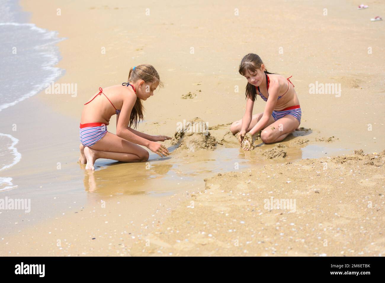 Deux filles construisent des châteaux de sable sur la mer Banque D'Images