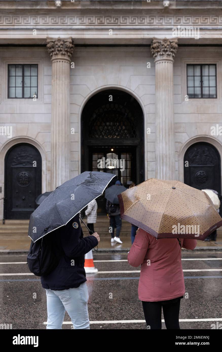 Les gens couvrent de la pluie d'hiver sous leurs parasols à l'extérieur de la Banque d'Angleterre, dans le Square Mile, City of London, UK Banque D'Images