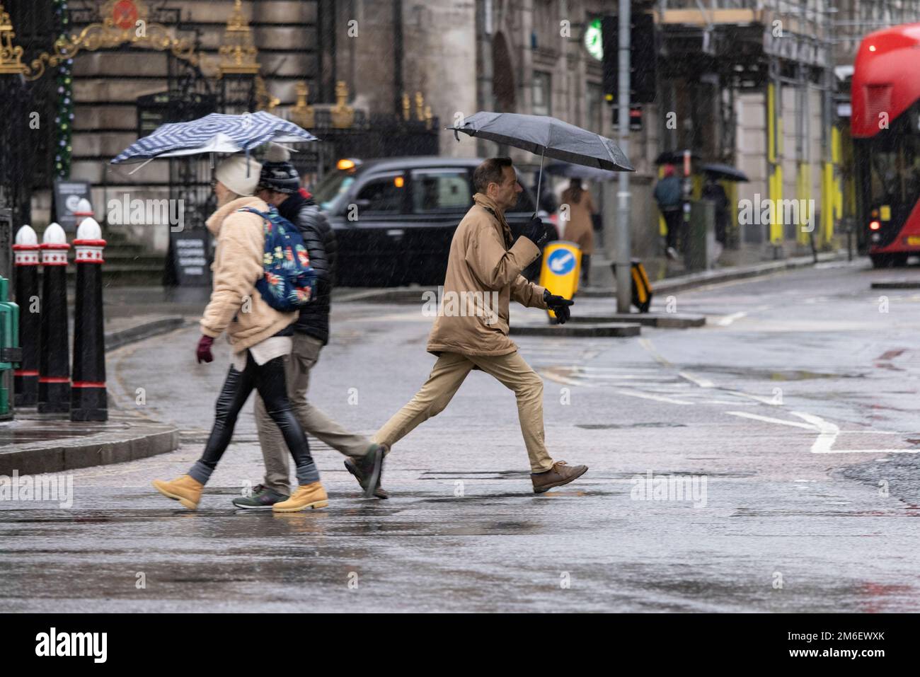 Les gens couvrent de la pluie d'hiver sous leurs parasols à l'extérieur de la Banque d'Angleterre, dans le Square Mile, City of London, UK Banque D'Images