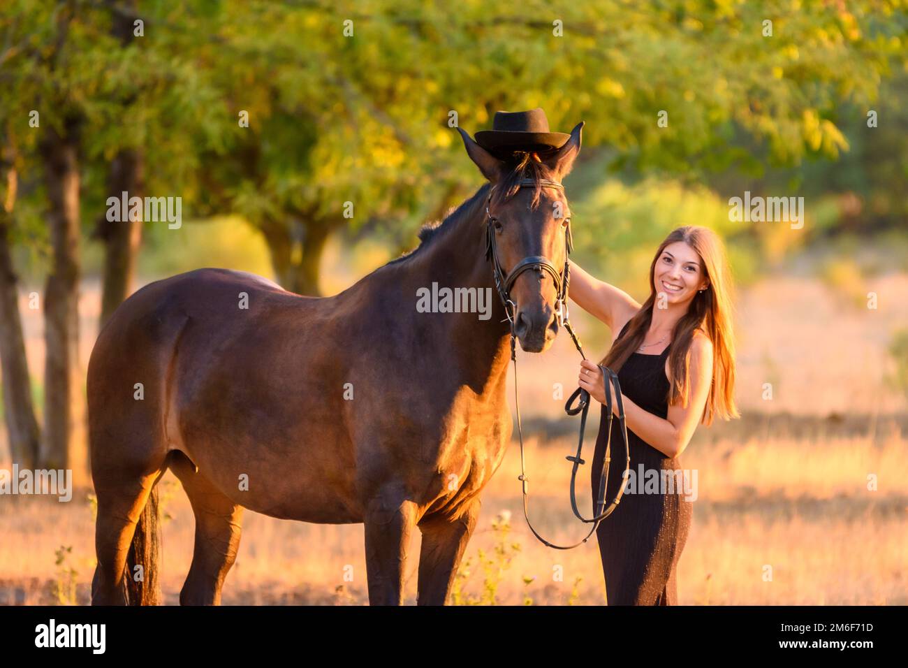La fille a mis un chapeau sur le cheval pour une marche et regarda heureusement dans le cadre, le portrait Banque D'Images