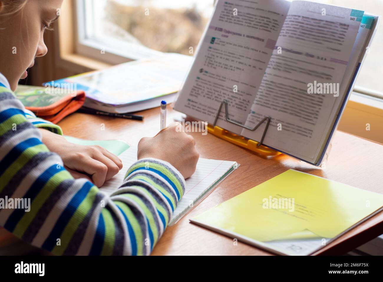 Fille à la maison devant la fenêtre faire les devoirs Banque D'Images