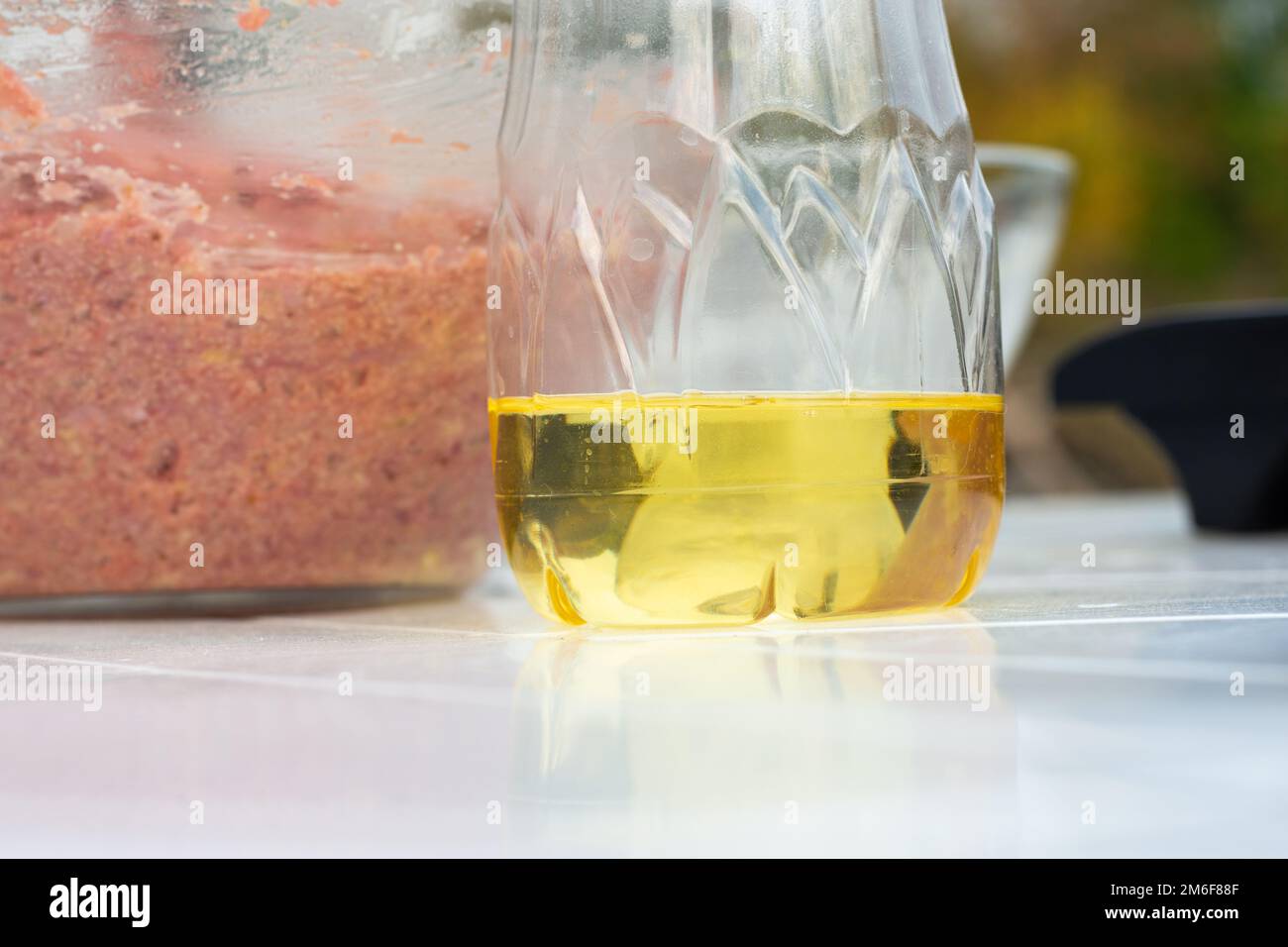 Sur la table est l'huile de tournesol dans une bouteille en plastique, dans le fond est un bol en verre avec la viande hachée pour les côtelettes Banque D'Images