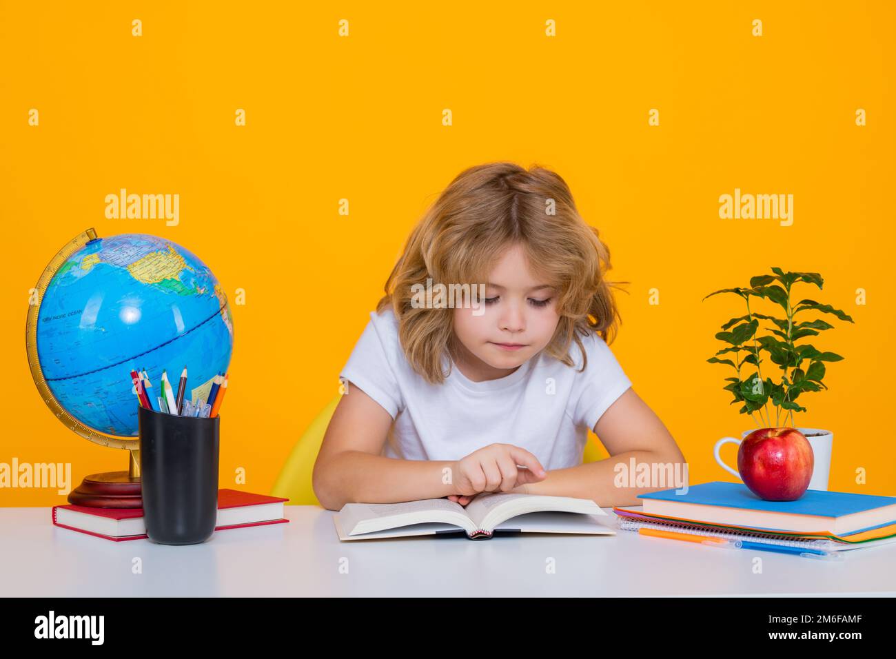 Livre de lecture pour enfant de l'école. Nerd élève garçon de l'école primaire avec livre isolé sur fond jaune studio. Intelligent génie intelligence enfant prêt à Banque D'Images