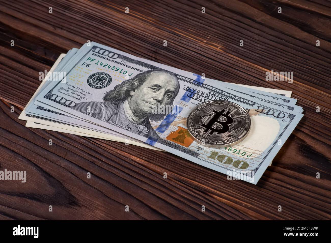 Pièce symbolique argent Bitcoin sur des billets de banque de cent dollars sur fond de bois. Échangez des bitcoins contre des dollars. Crypto-monnaie sur les États-Unis Banque D'Images
