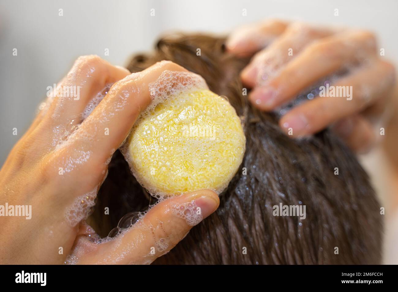 Un homme applique une barre de shampooing solide aux cheveux. Homme dans la salle de bains. Soins capillaires durables, cosmétiques écologiques. Sans plastique, aucun gaspillage Banque D'Images