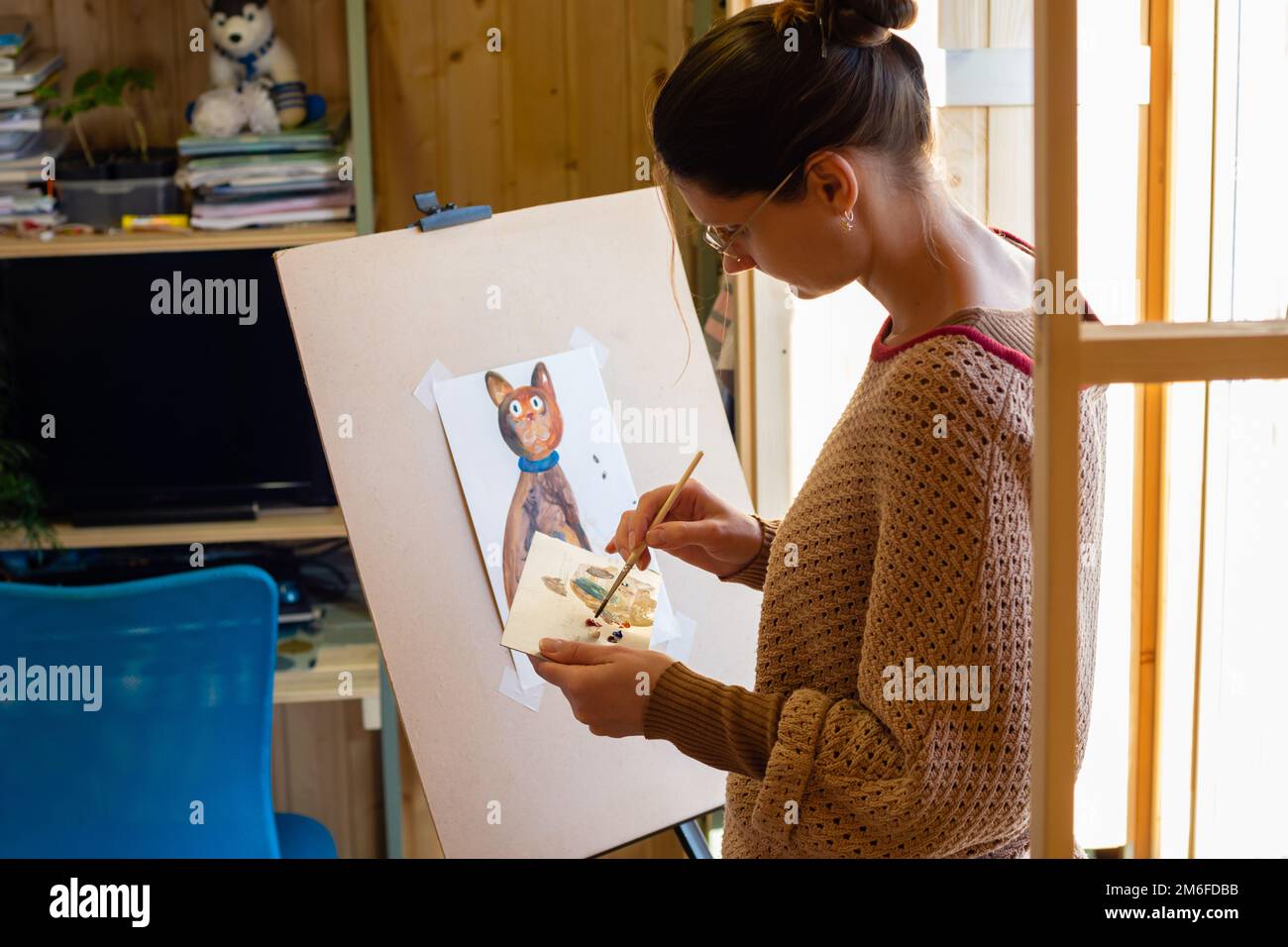 L'artiste mélange des peintures sur une palette de peinture à la maison par la fenêtre Banque D'Images