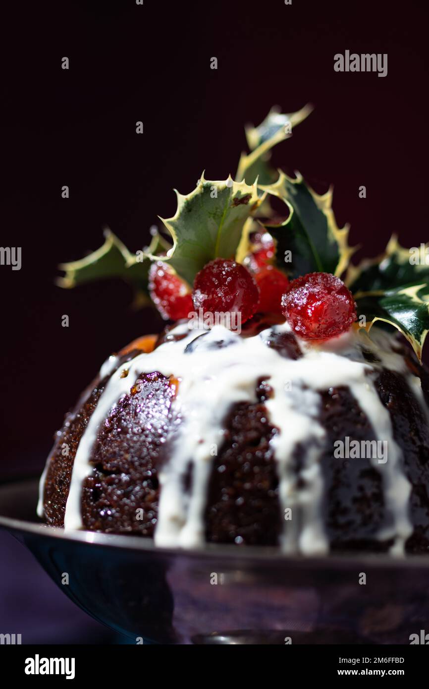 Dessert traditionnel aux fruits de Noël, décoré de cerises et de feuilles, dans un décor rouge, bleu et violet chaud classique Banque D'Images