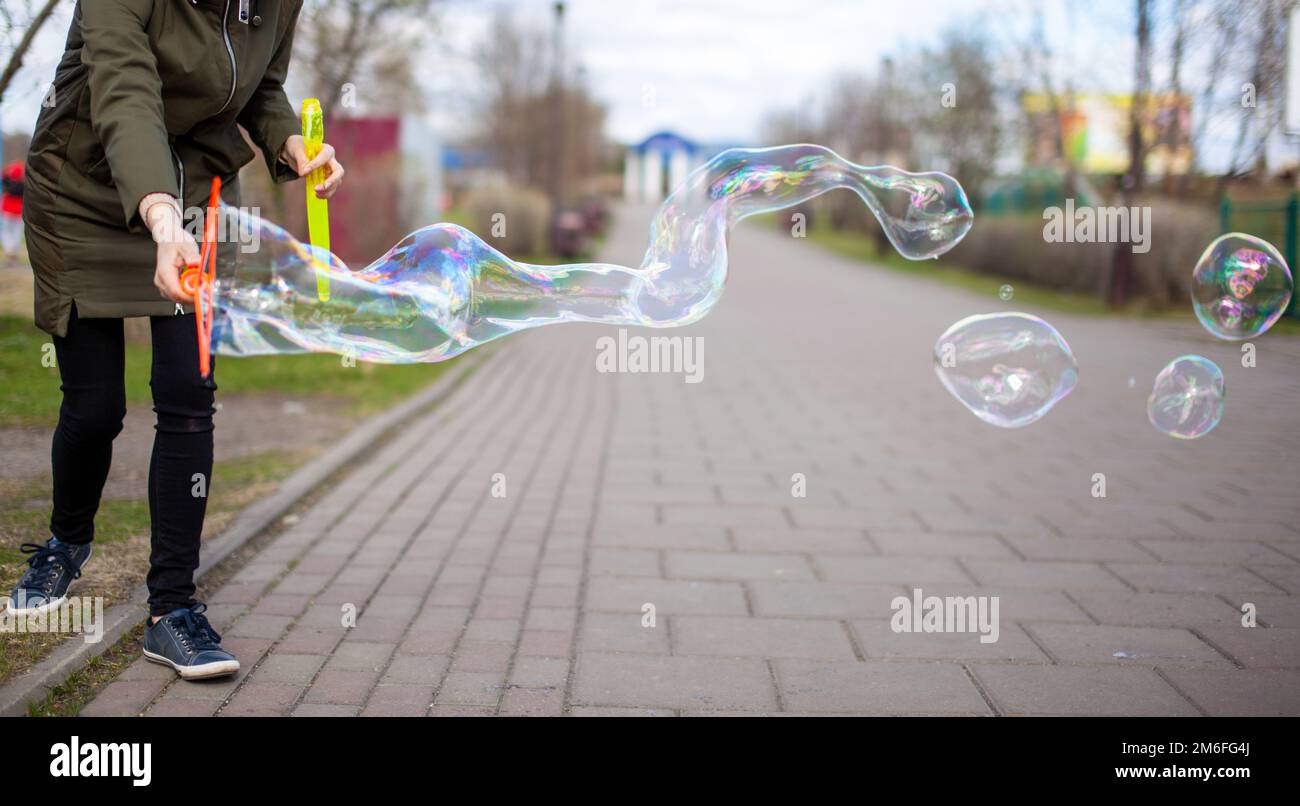 Une fille souffle des bulles de savon dans le parc pour le divertissement des enfants Banque D'Images