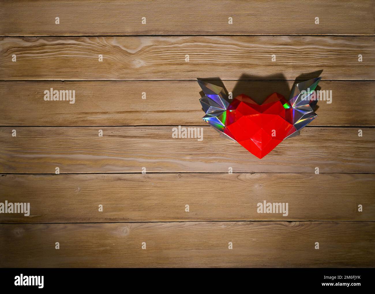 coeur en papier polygonal rouge sur fond en bois. ombres dures. copier l'espace Banque D'Images