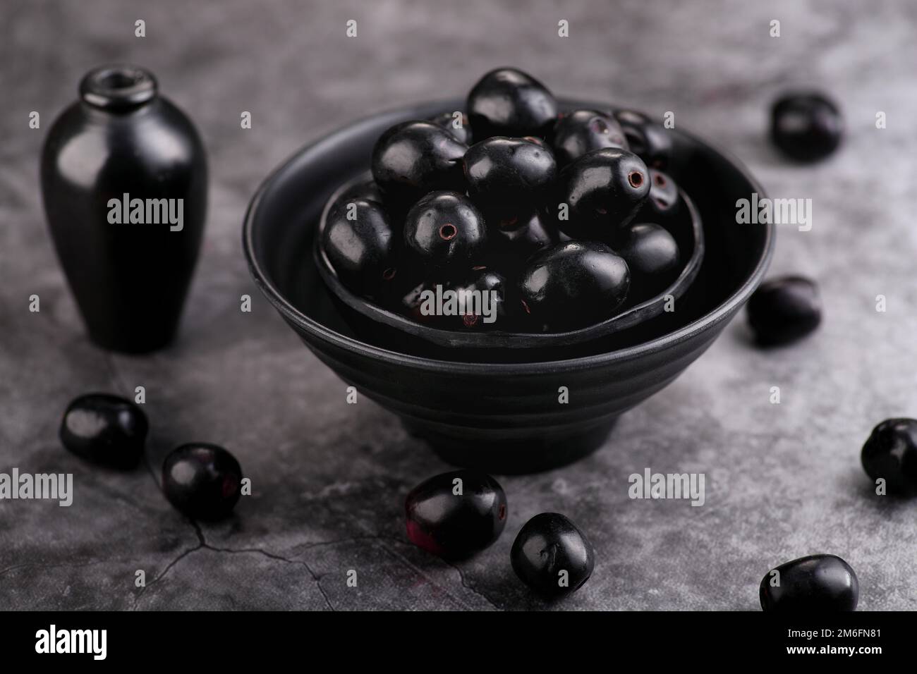 Fruit indien de baie noire ou de Jamun, prune de Java dans un bol noir - H Banque D'Images