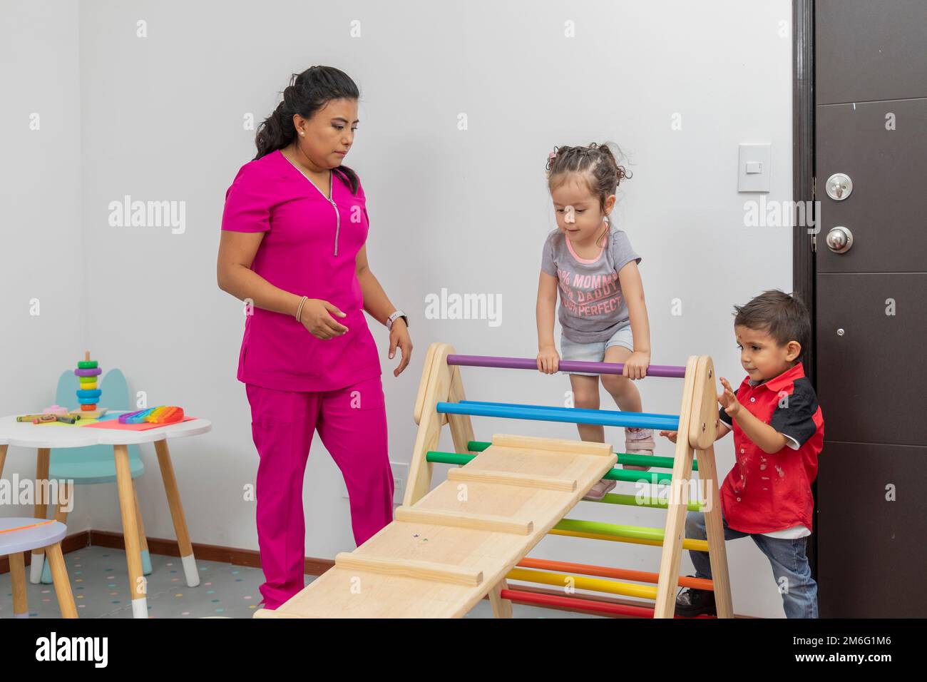 Femme médecin donnant la consultation à deux enfants dans la salle de jeux de son bureau. Banque D'Images