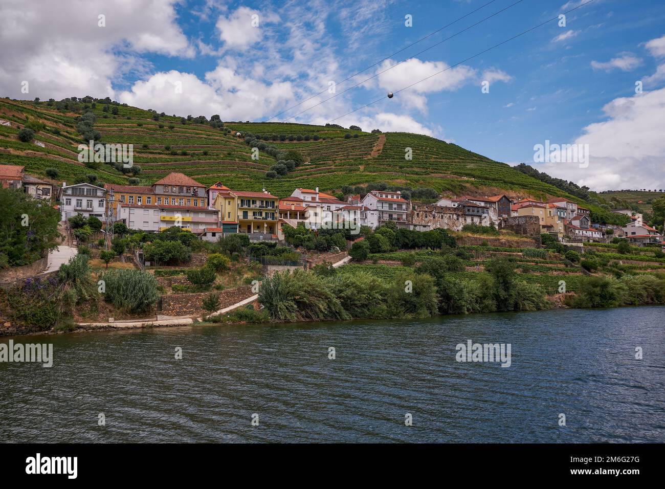 Petit village à Riverfront - vue depuis le bateau de croisière dans la vallée du fleuve Douro - région viticole du port avec des fermes de terrasses sculptées à M Banque D'Images