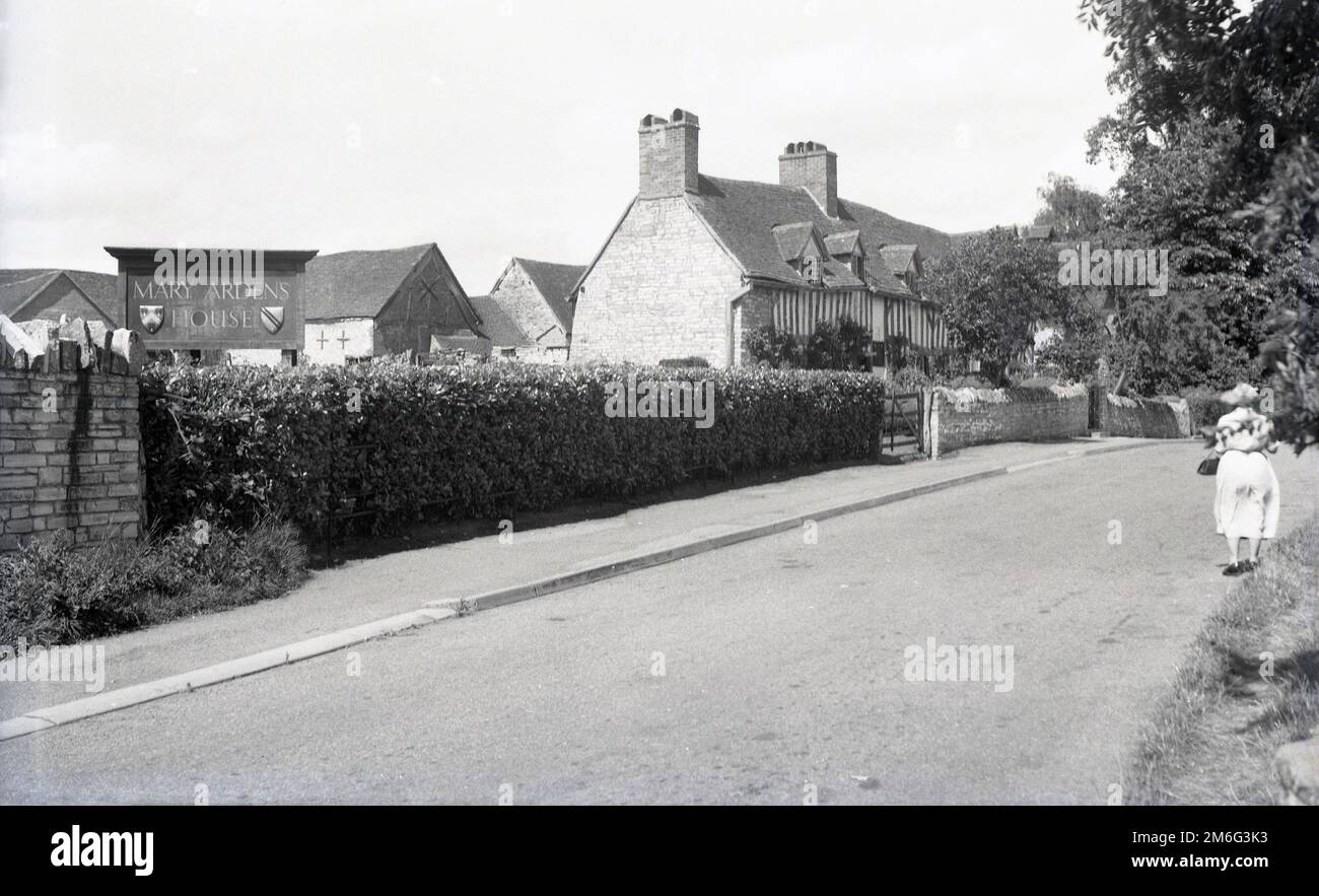 1950s, historique, une dame se tenant dans une route à l'extérieur de la maison de Mary Arden, la maison d'enfance de la mère du dramaturge anglais William Shakespeare, Wilmcote, près de Stratford-upon-Avon, Angleterre, Royaume-Uni. Banque D'Images