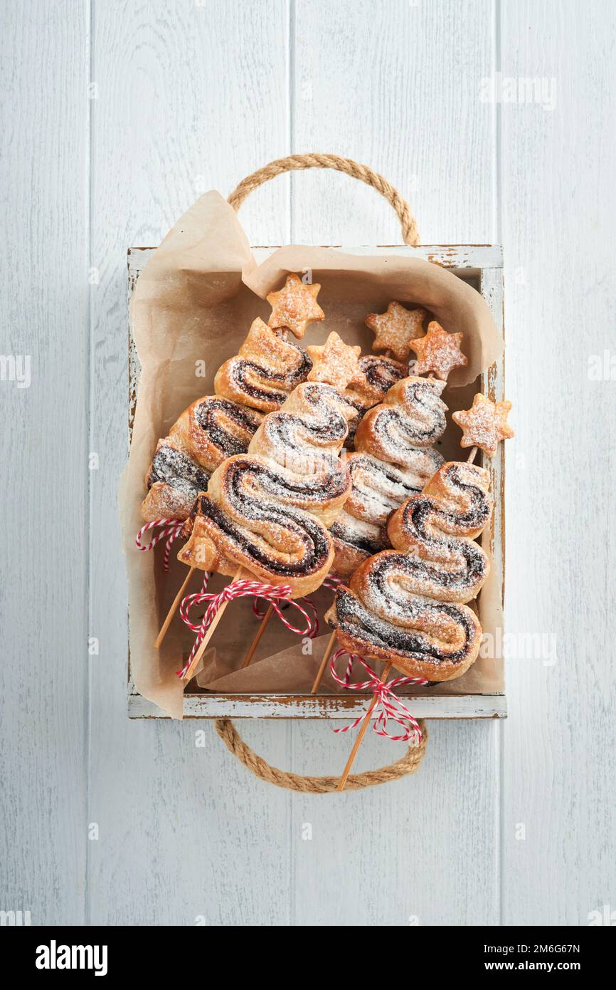 Gâteau feuilleté en forme d'arbre de Noël avec garniture au chocolat, poudre de sucre et sucettes sur fond de bois blanc ancien. Noël, nouvel an Banque D'Images