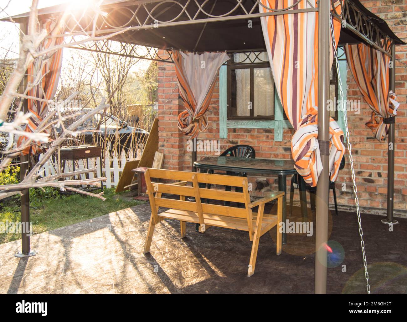 Une belle aire de loisirs pour une famille dans une maison de campagne, une tente avec un banc et une table sur le fond d'une maison en briques Banque D'Images