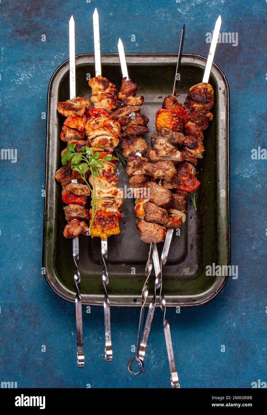 Brochettes de viande de porc, de poulet et de légumes grillées au barbecue sur plateau Vue de dessus, plan d'agencement. Arrière-plan bleu. Banque D'Images