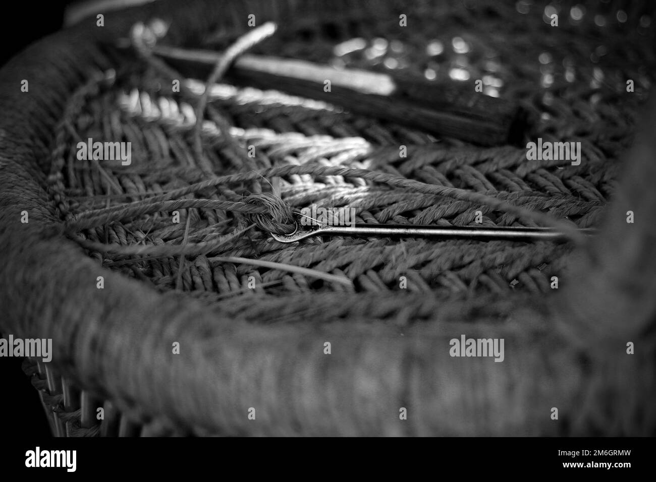 Un artisan qualifié travaillant manuellement un fauteuil en bambou détaillé avec ses doigts et ses outils Banque D'Images