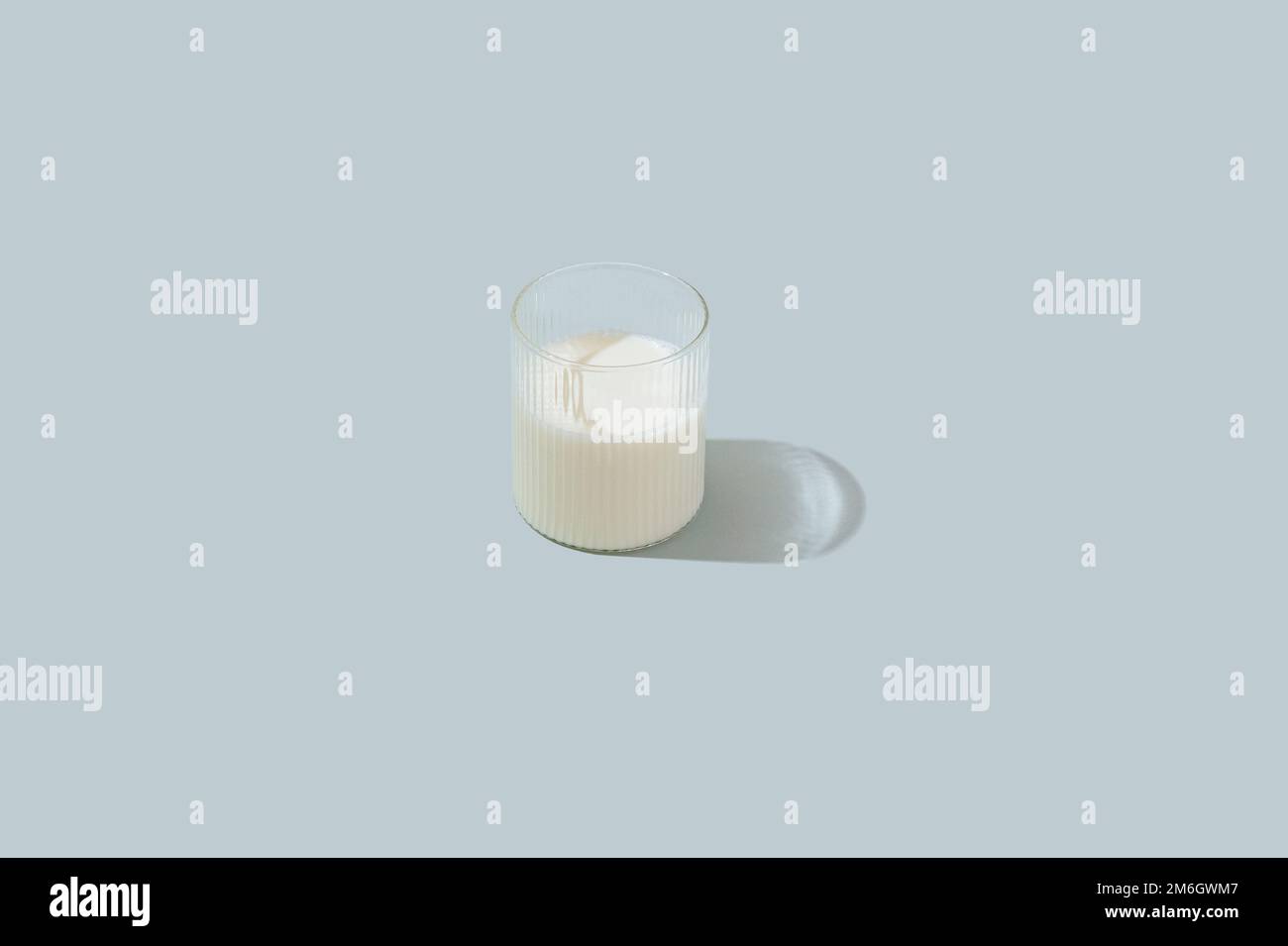 du lait dans un verre transparent sur fond bleu clair Banque D'Images