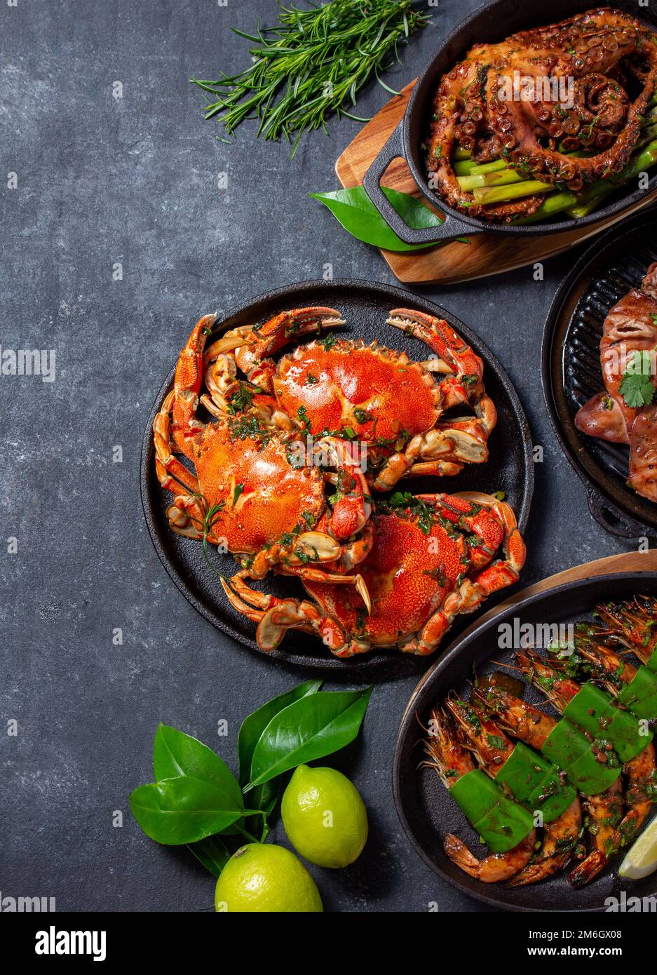 Ensemble de plats de fruits de mer. Crabes, poulpes, calmars et crevettes tigrées sur des casseroles en fonte et des assiettes sur fond noir. Vue de dessus. Copier l'espace pour le texte Banque D'Images