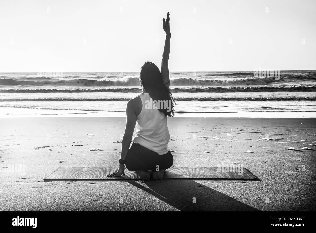 Photo d'une jeune femme pratiquant le yoga à la plage. Photographie en noir et blanc Banque D'Images