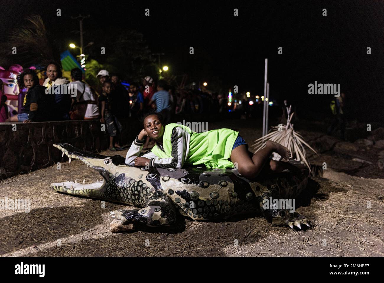 Femme couché sur le crocodile papier maché, mannequin, festival folklorique Boulevard Poincare, nuit, peuple, Mahajanga, Madagascar Banque D'Images