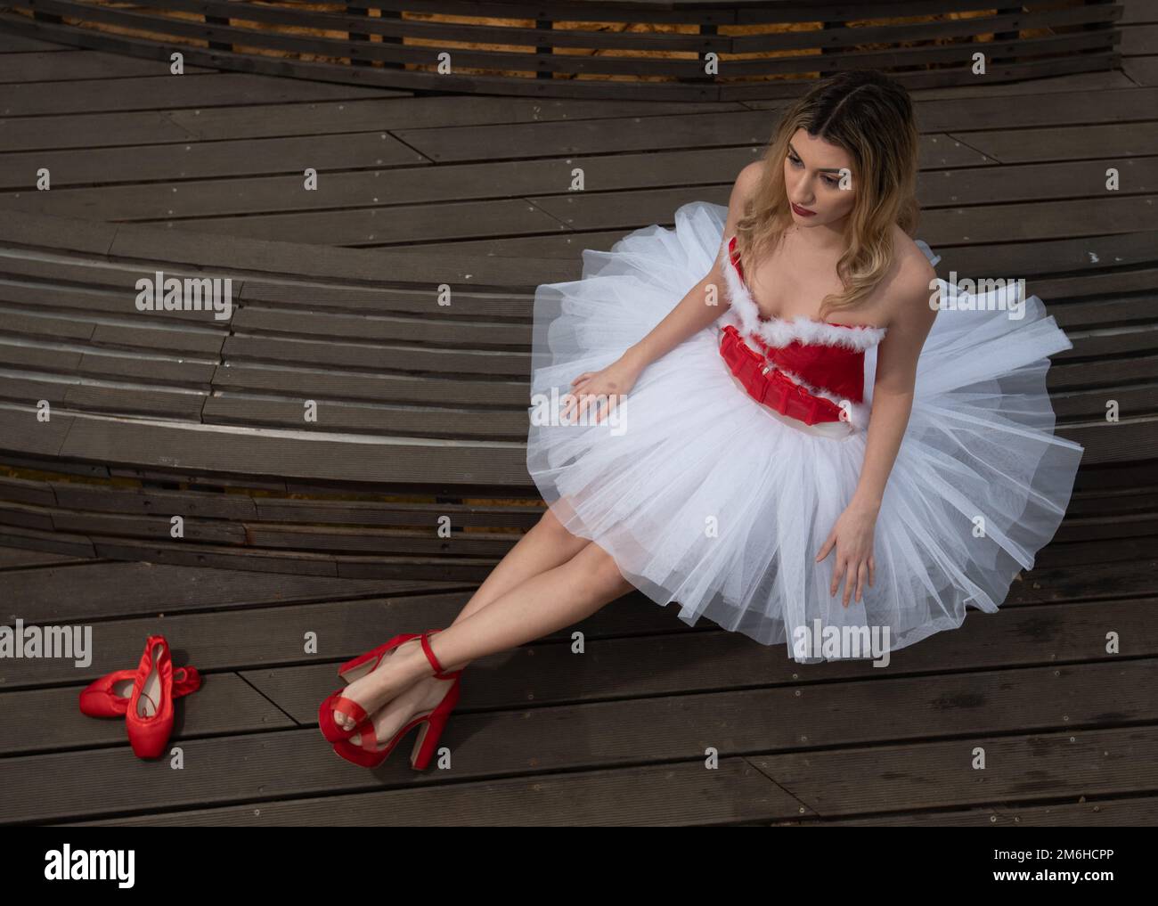 Ballerine portant la robe rouge blanche de noël posant sur le sol Banque D'Images