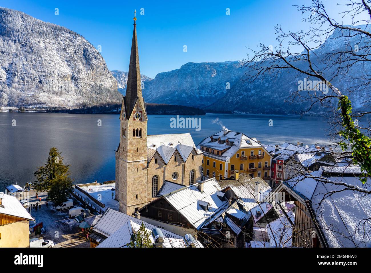 Beau paysage urbain ensoleillé de la ville spéciale Hallstatt en Autriche Salzkammergut neige hiver montagnes et lac et église . Banque D'Images