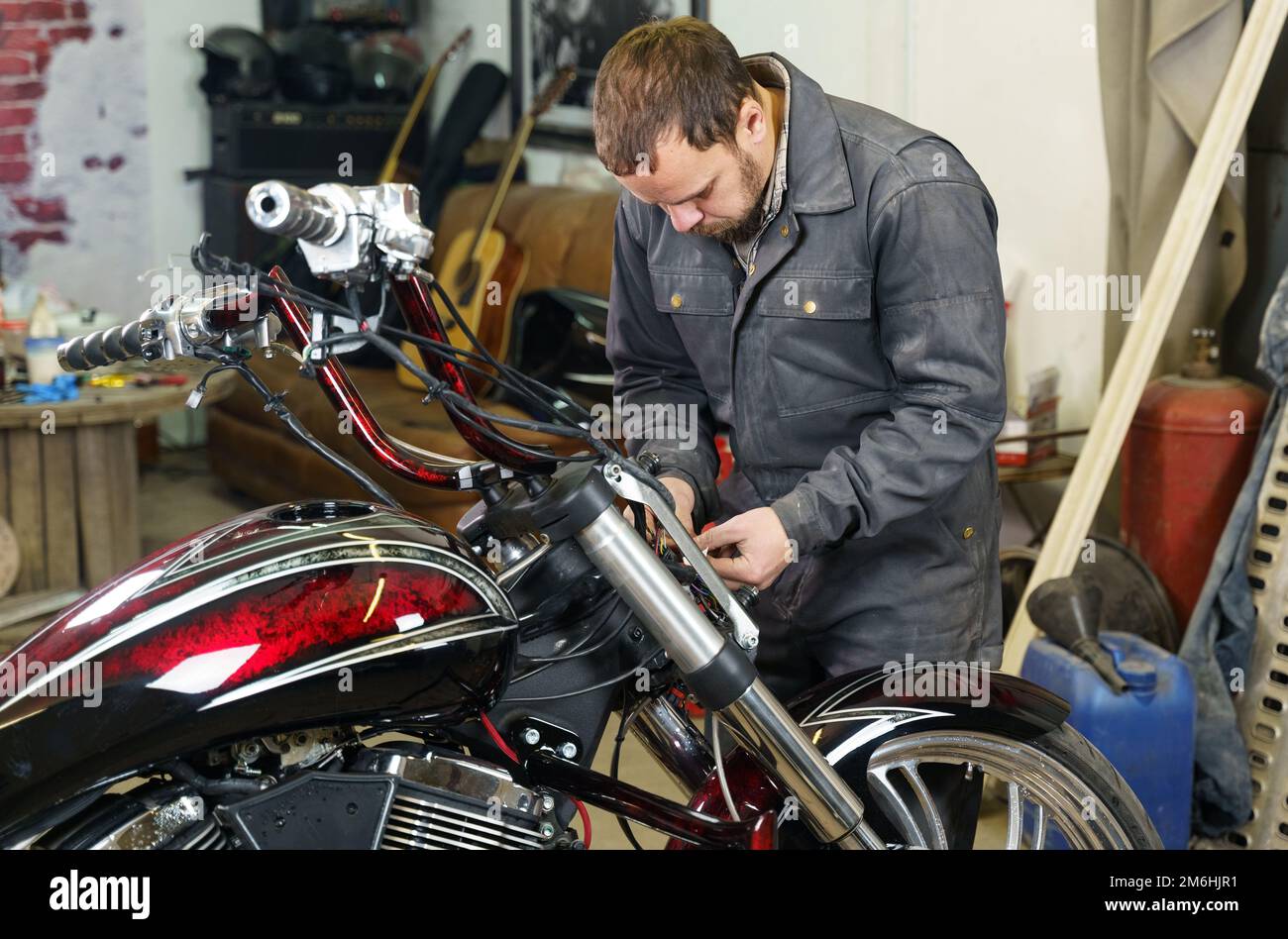 Le mécanicien connecte les câbles électriques de la moto. Concept de transport. Banque D'Images