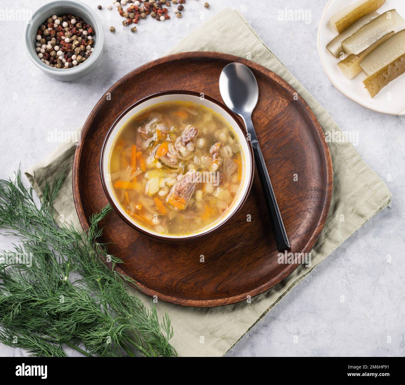 Soupe russe traditionnelle avec concombres marinés. Pickle avec de l'orge perlé et de la viande sur un fond clair avec de l'aneth frais et des épices. Vue de dessus Banque D'Images