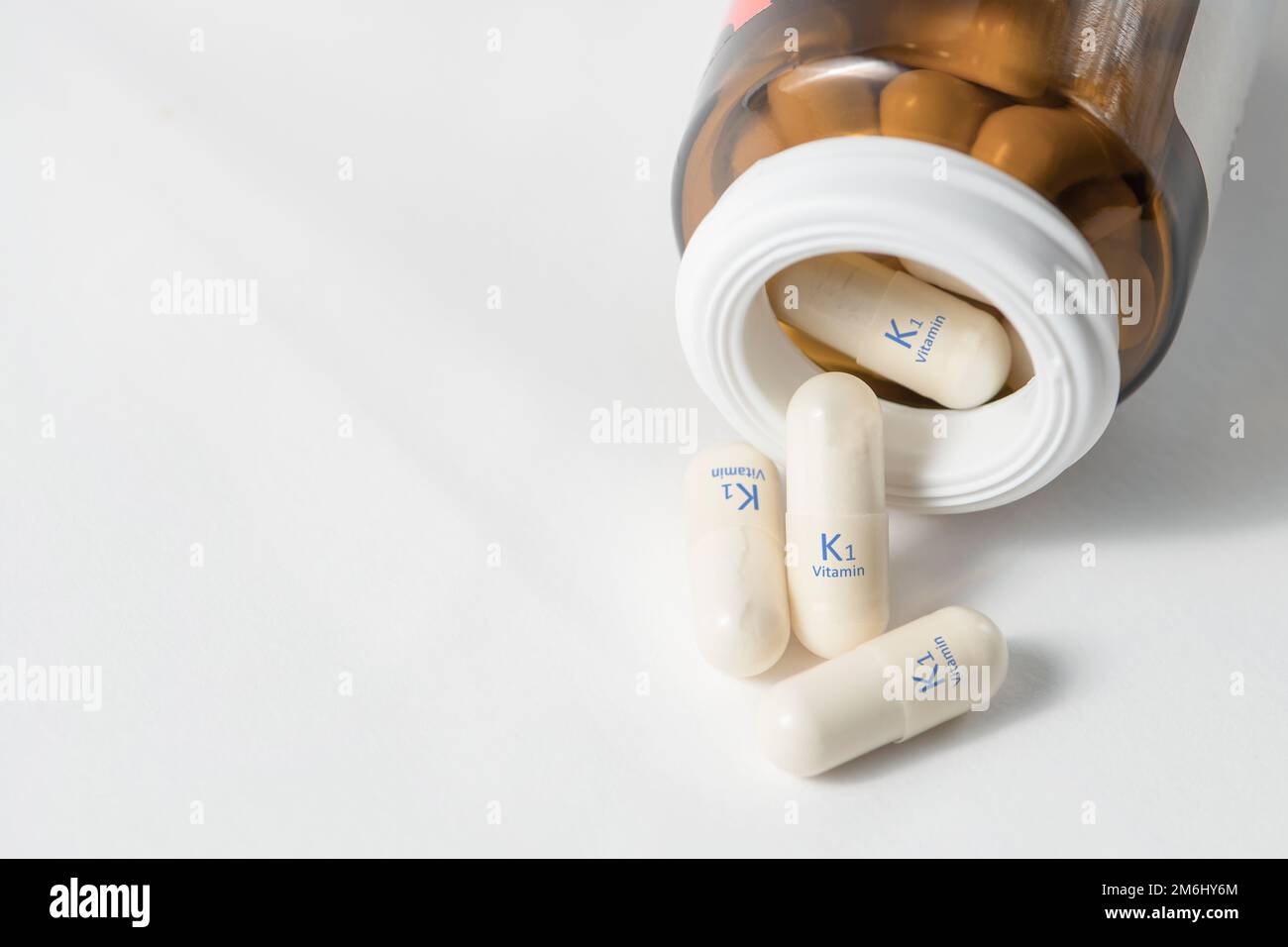 Vitamine K1.les capsules avec phylloquinone augmentent la coagulation sanguine, stimulent la cicatrisation des plaies. Des capsules blanches de vitamine K1 ou de phylloquinone sont dispersées Banque D'Images
