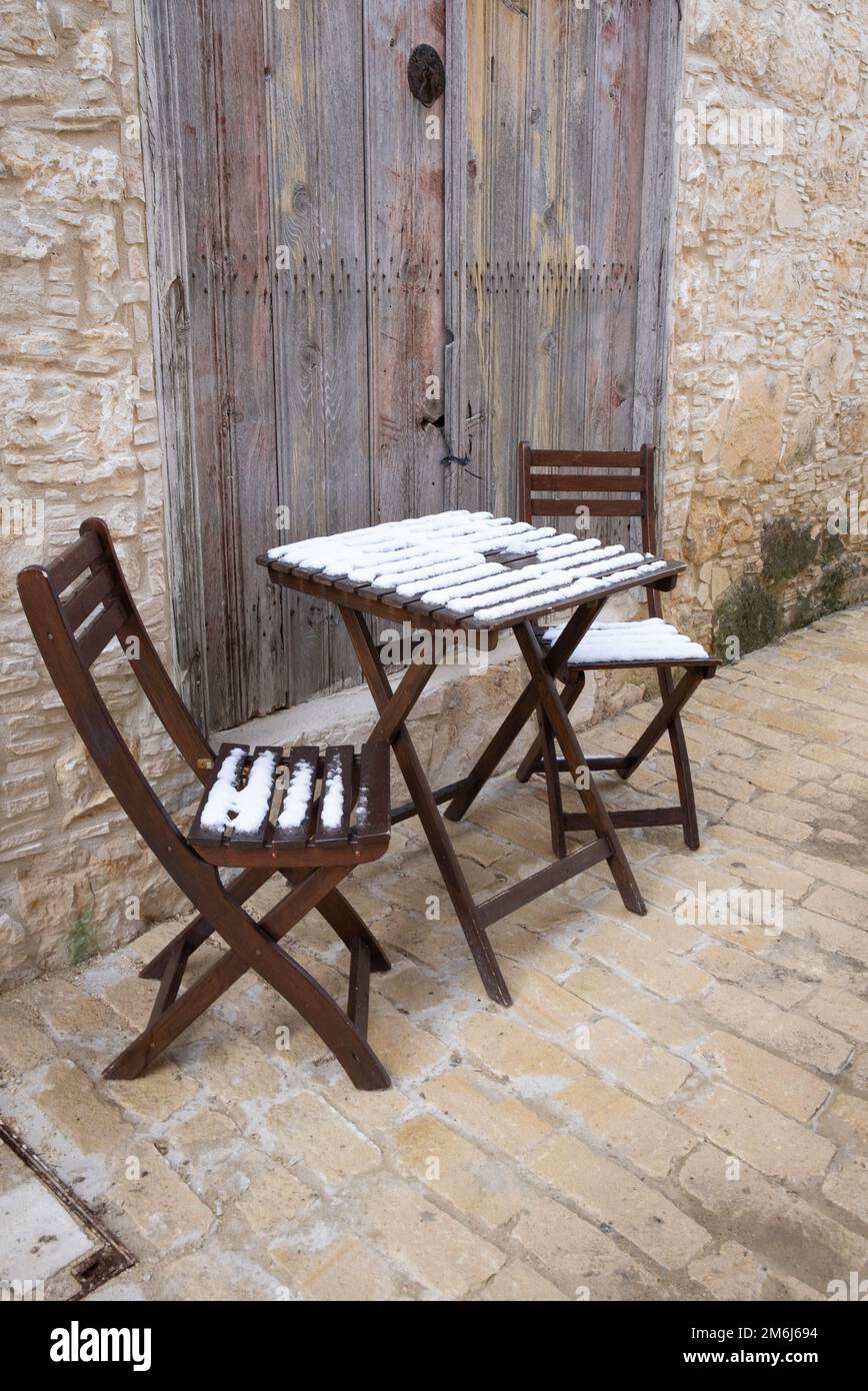 Vider les chaises en bois recouvertes de neige et la table basse sur un sentier laqué. Banque D'Images