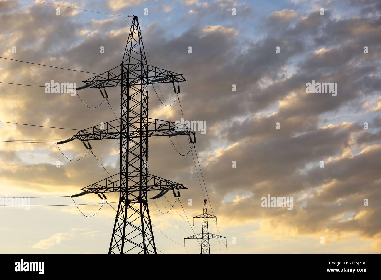 Silhouettes de tours haute tension avec fils électriques sur fond de ciel et de nuages de coucher de soleil. Lignes de transmission d'électricité, concept d'alimentation Banque D'Images