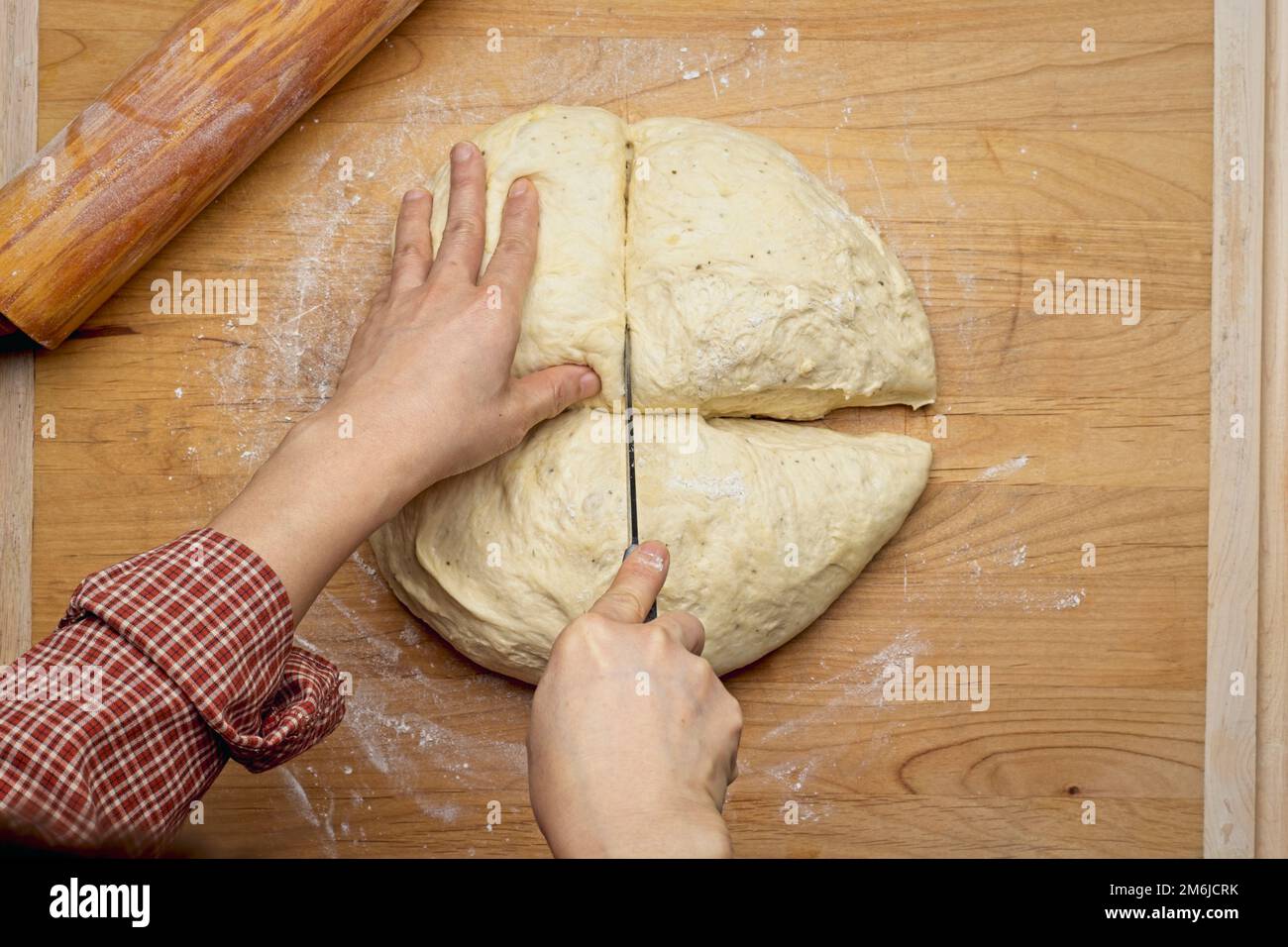 Photo à plat d'une boule de pâte coupée sur une grande planche à découper en bois à déployer. Banque D'Images