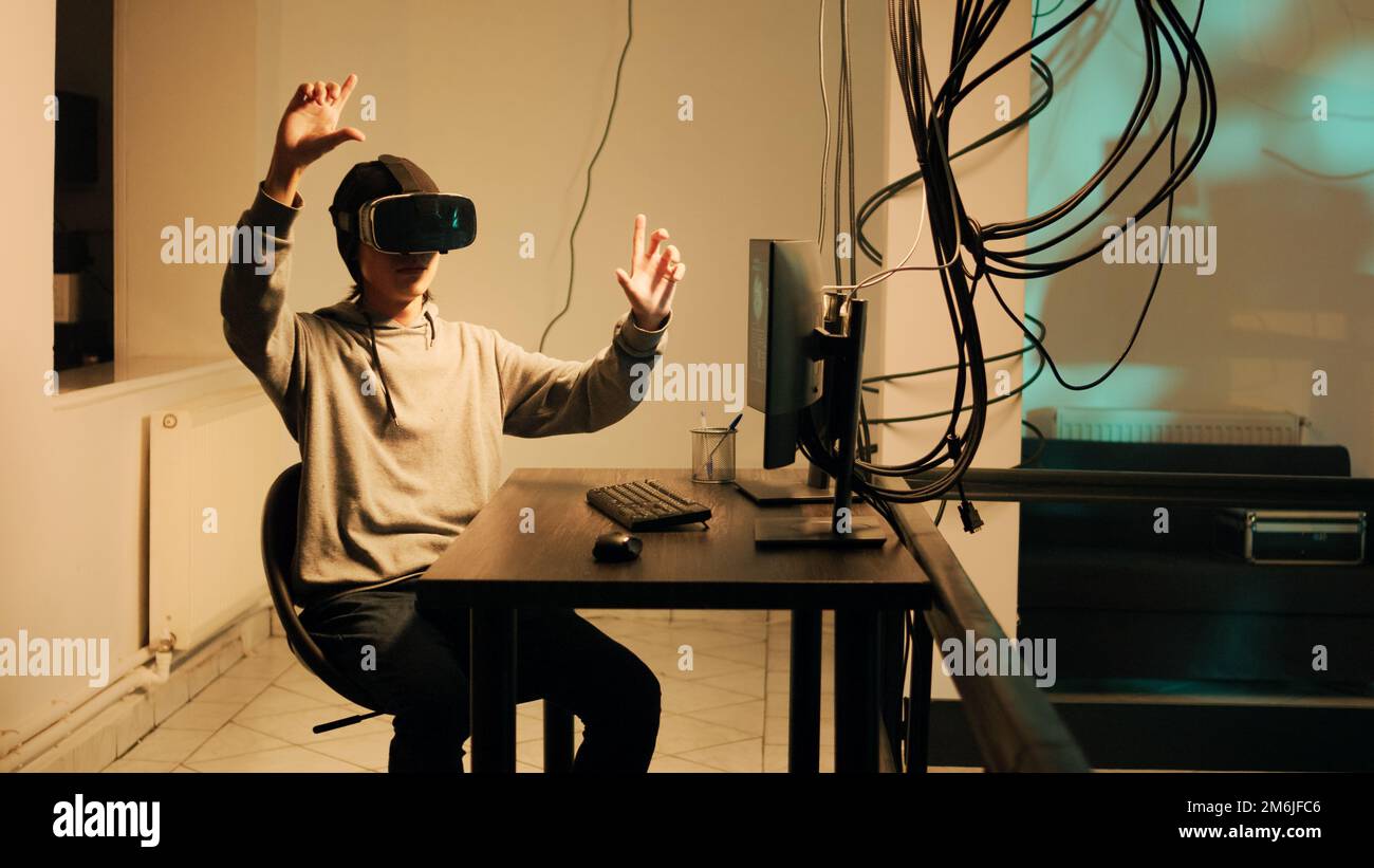 Jeune voleur qualifié travaillant avec des lunettes vr pour pirater le cryptage de pare-feu, en utilisant le casque de réalité virtuelle pour briser le système gouvernemental. Hacker masculin brisant le réseau avec des programmes malveillants et des virus. Banque D'Images
