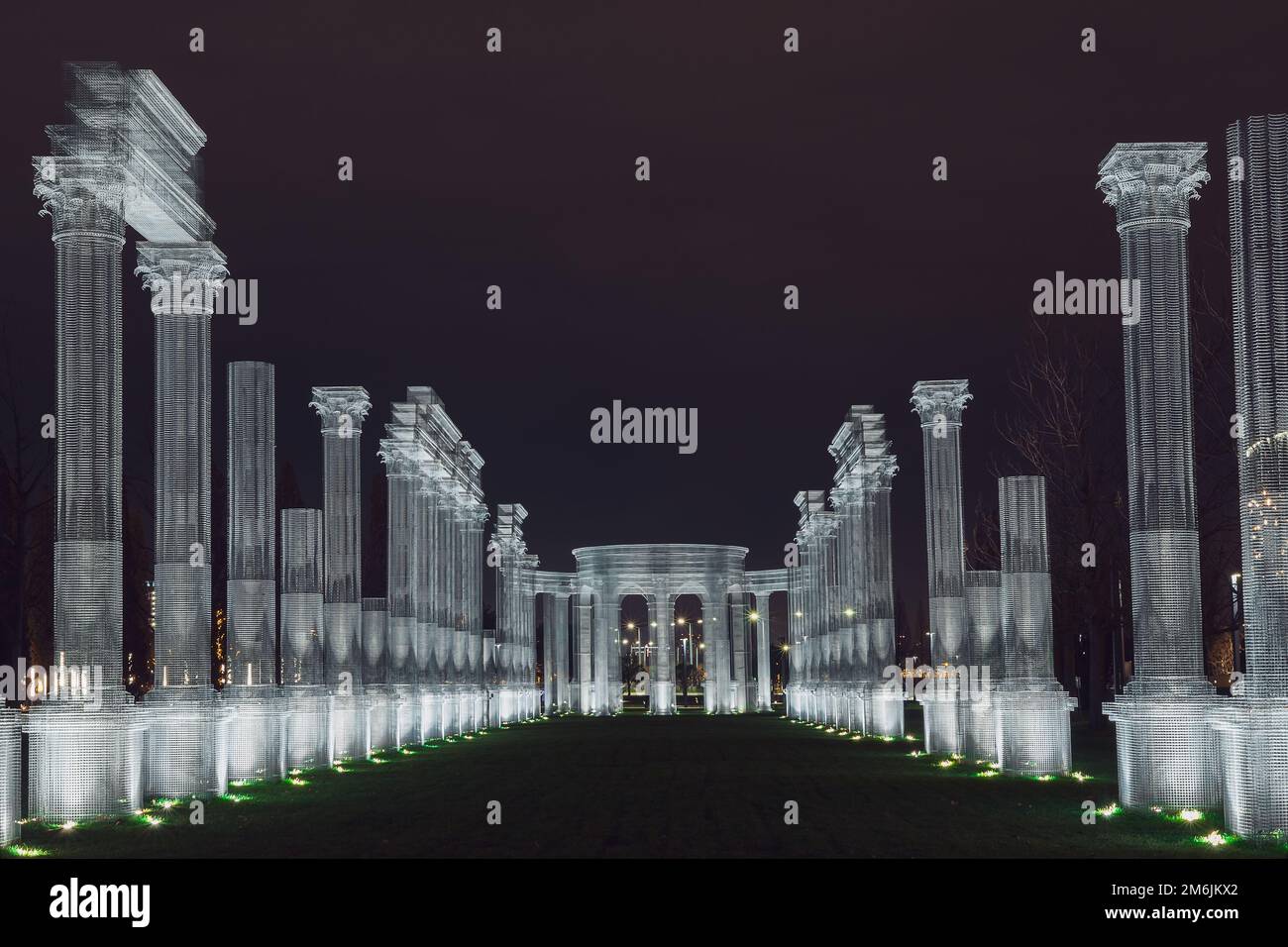 Russie, Krasnodar 07.01.2022. Cadre blanc la colonnade lumineuse décore une allée verte dans le parc de nuit sous un ciel sombre Banque D'Images