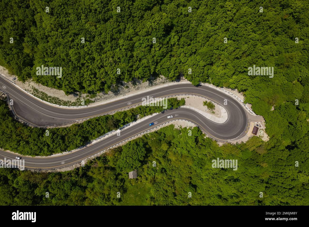 Vue aérienne de la route sinueuse depuis le col de haute montagne. Super voyage en voiture à travers les bois denses. Vue sur les oiseaux. Banque D'Images