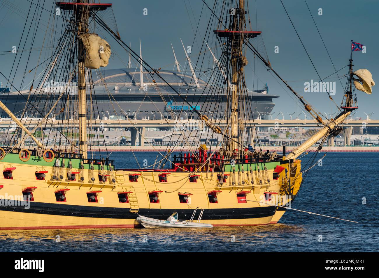 Russie, St. Petersbourg, 20 mai 2022 : une ancienne frégate de voile navigue sur la mer calme au coucher du soleil, le nouveau stade Gazprom Arena b Banque D'Images