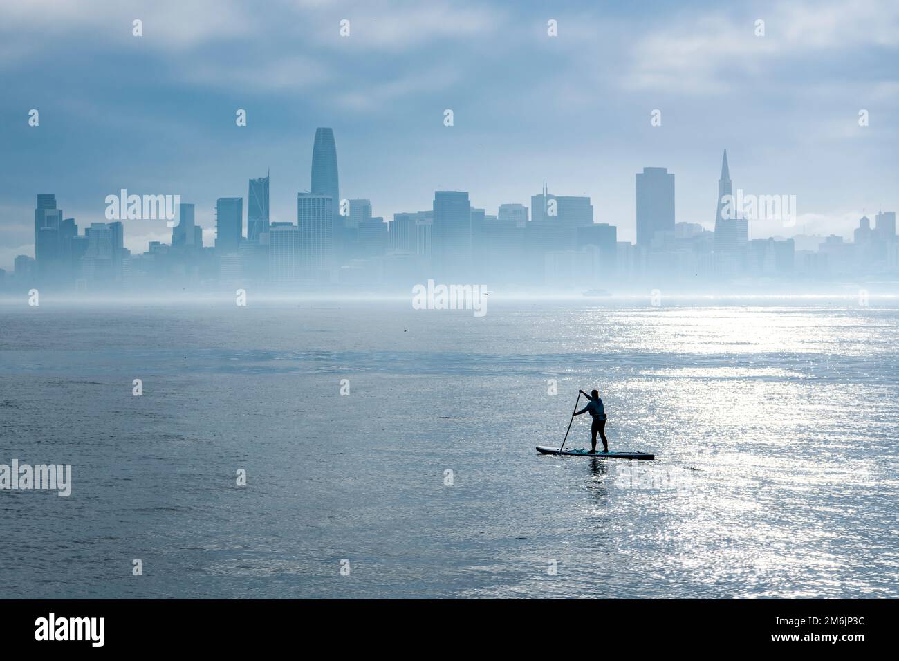 femme paddleboard dans la baie avec horizon de la ville Banque D'Images