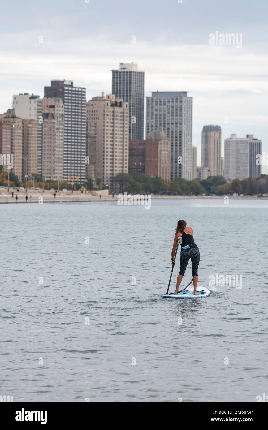 Vue arrière de la femme paddleboard dans le lac avec la ville en arrière-plan Banque D'Images