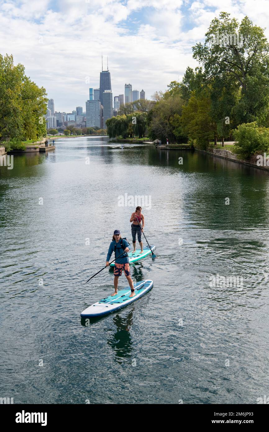 Homme et femme paddleboard dans la rivière avec la ville en arrière-plan Banque D'Images