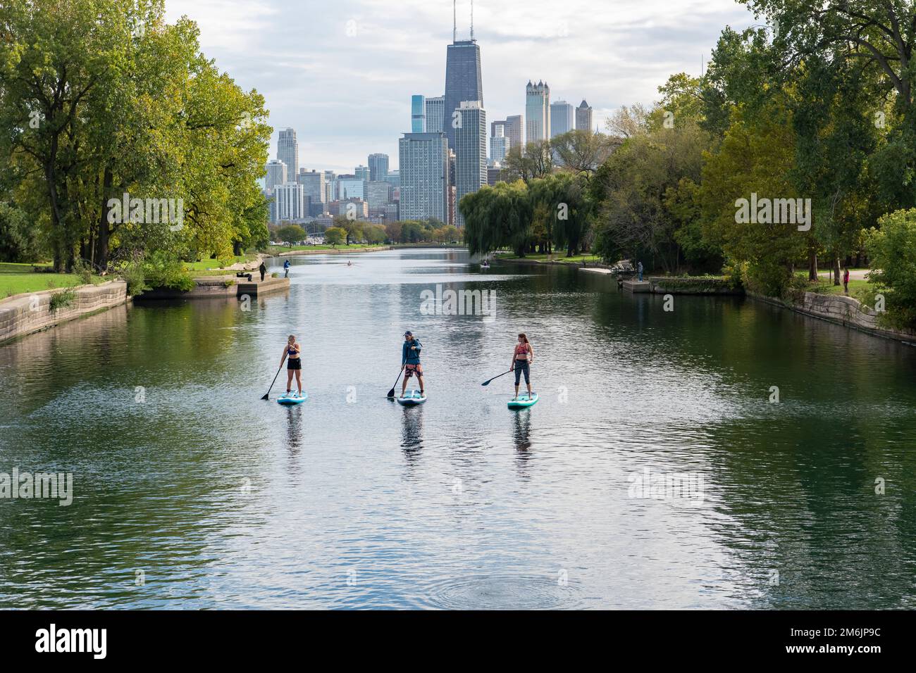 amis paddleboard dans la rivière avec la ville en arrière-plan Banque D'Images