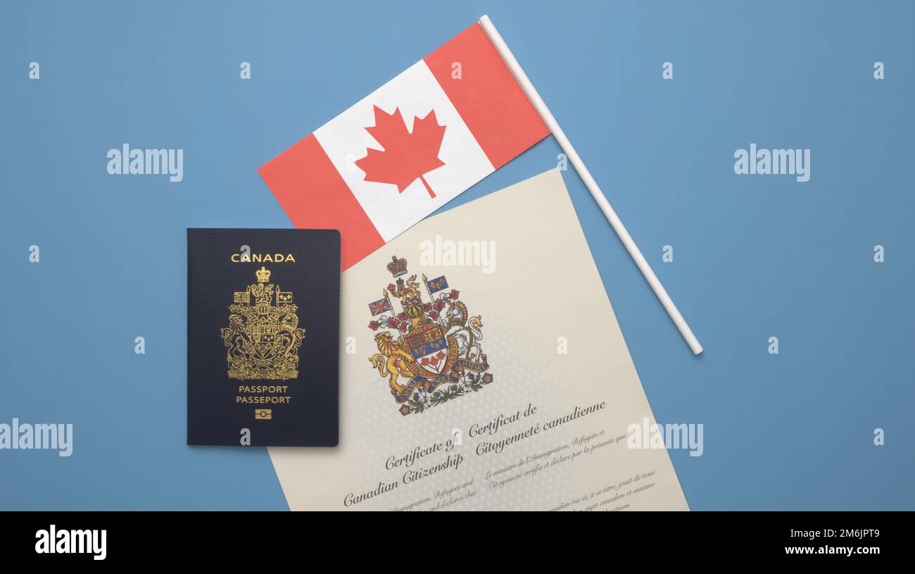 Un passeport canadien sur un drapeau canadien et un certificat de citoyenneté canadienne sur fond bleu clair et solide Banque D'Images