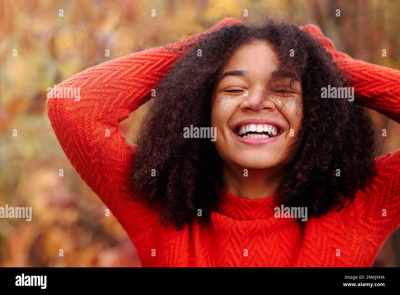 Jeune heureuse femme afro-américaine pleine de joie avec les yeux fermés et riant dans la forêt d'automne Banque D'Images