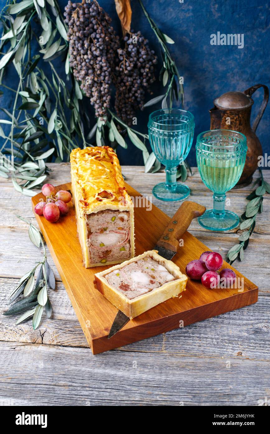 Plat français traditionnel en route avec viande de lapin et filet de porc servi avec des raisins en gros plan sur un boa en bois de conception moderne Banque D'Images