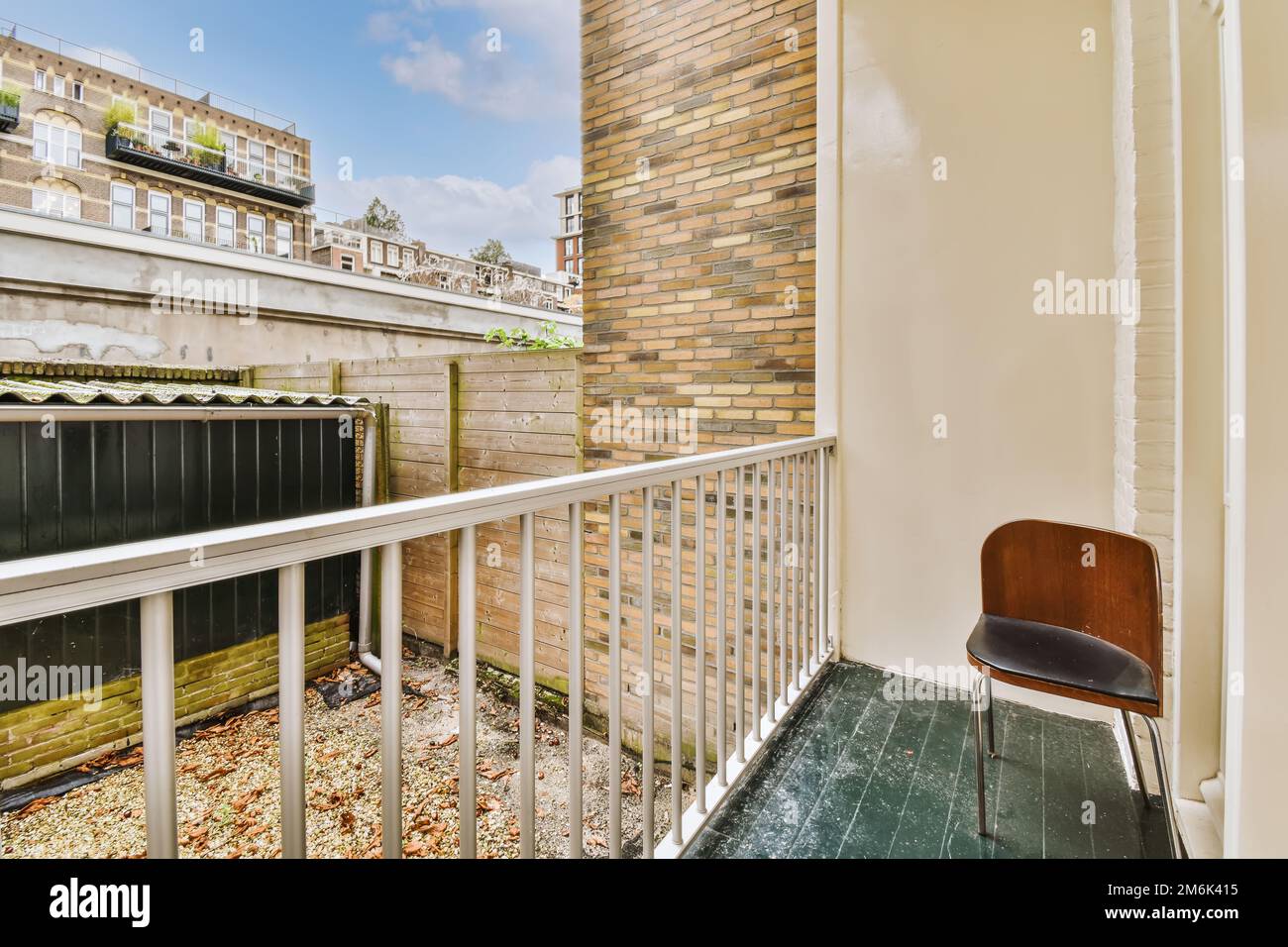 un balcon avec une chaise sur le côté gauche et un mur de briques sur la droite, en face Banque D'Images